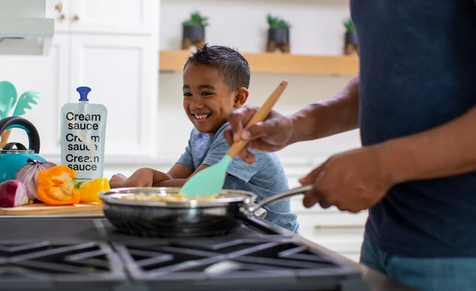 Child and an adult cooking, using the SIG aerocap aseptic pouch (photo)