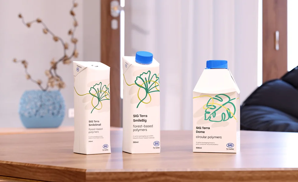 The image features a table with three cartons of milk sitting on top of it. The milk cartons are of different sizes and are placed next to each other.