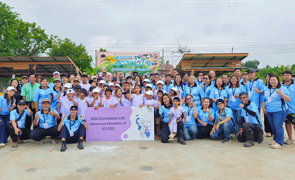 A large group of adults and children posing outdoors with a donation banner (photo)
