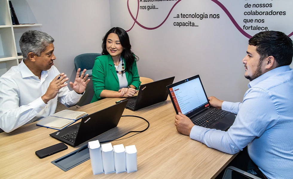 Three colleagues having a meeting with laptops in a conference room (photo)
