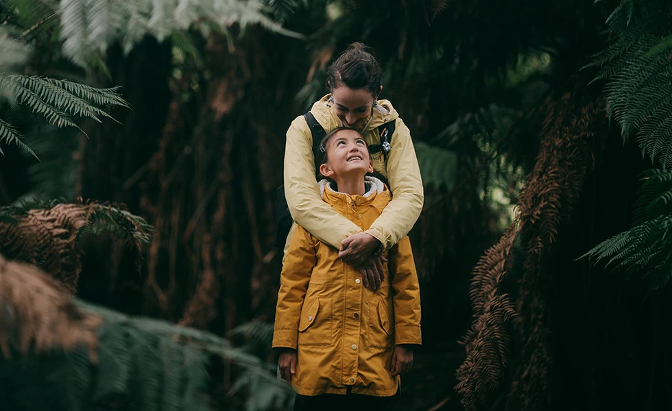 A woman hugging a smiling child in a forest (photo)