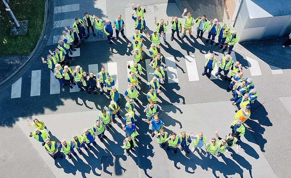 A group of workers in safety vests forming the letters SIG (photo)